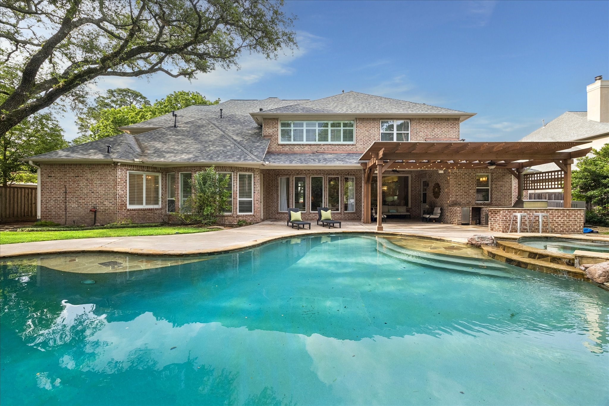 11421 Whippoorwill Road Houston, TX 77024 - Photo 27 of 33 Magnificent rear view of the property highlighting the custom pool and spa oasis. The grounds feature extensive flagstone decking, a professional summer kitchen under a cedar pergola, and a massive covered patio. Perfectly framed by majestic shade trees, this backyard is an entertainer's dream.