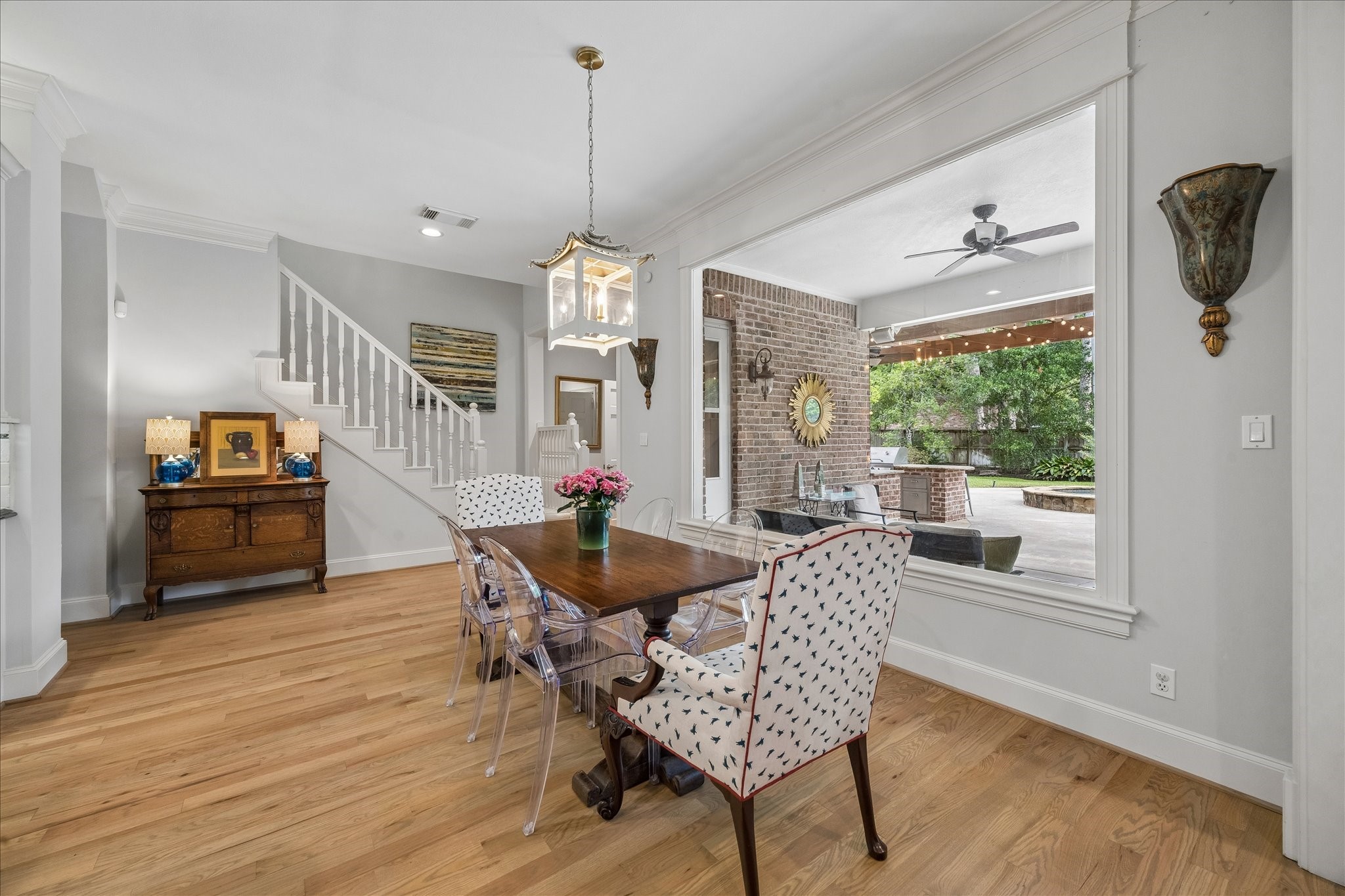 11421 Whippoorwill Road Houston, TX 77024 - Photo 4 of 33 Start your mornings with a view! This bright breakfast room features a massive picture window that frames the pool and outdoor kitchen perfectly. With its designer lantern pendant and rich hardwoods, this space offers a seamless connection to both the back staircase and the main living areas, making it the heart of daily family life.