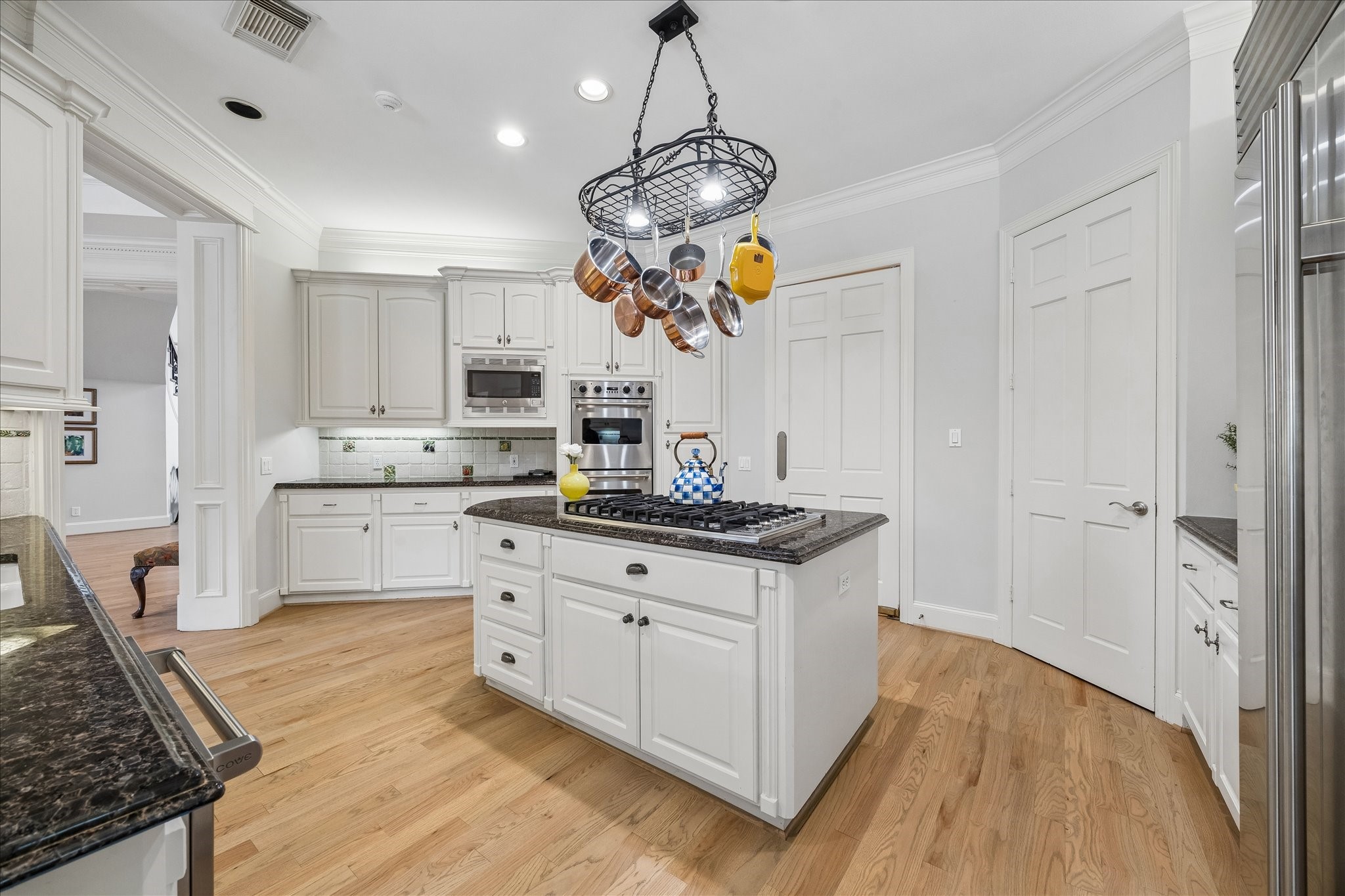 11421 Whippoorwill Road Houston, TX 77024 - Photo 6 of 33 Functional elegance meets classic design in this spacious kitchen, boasting ample storage and an intuitive layout. Highlights include double wall ovens, a spacious pantry, and a functional island that doubles as a prep station. The bright, neutral palette and under-cabinet lighting create a warm and inviting atmosphere.
