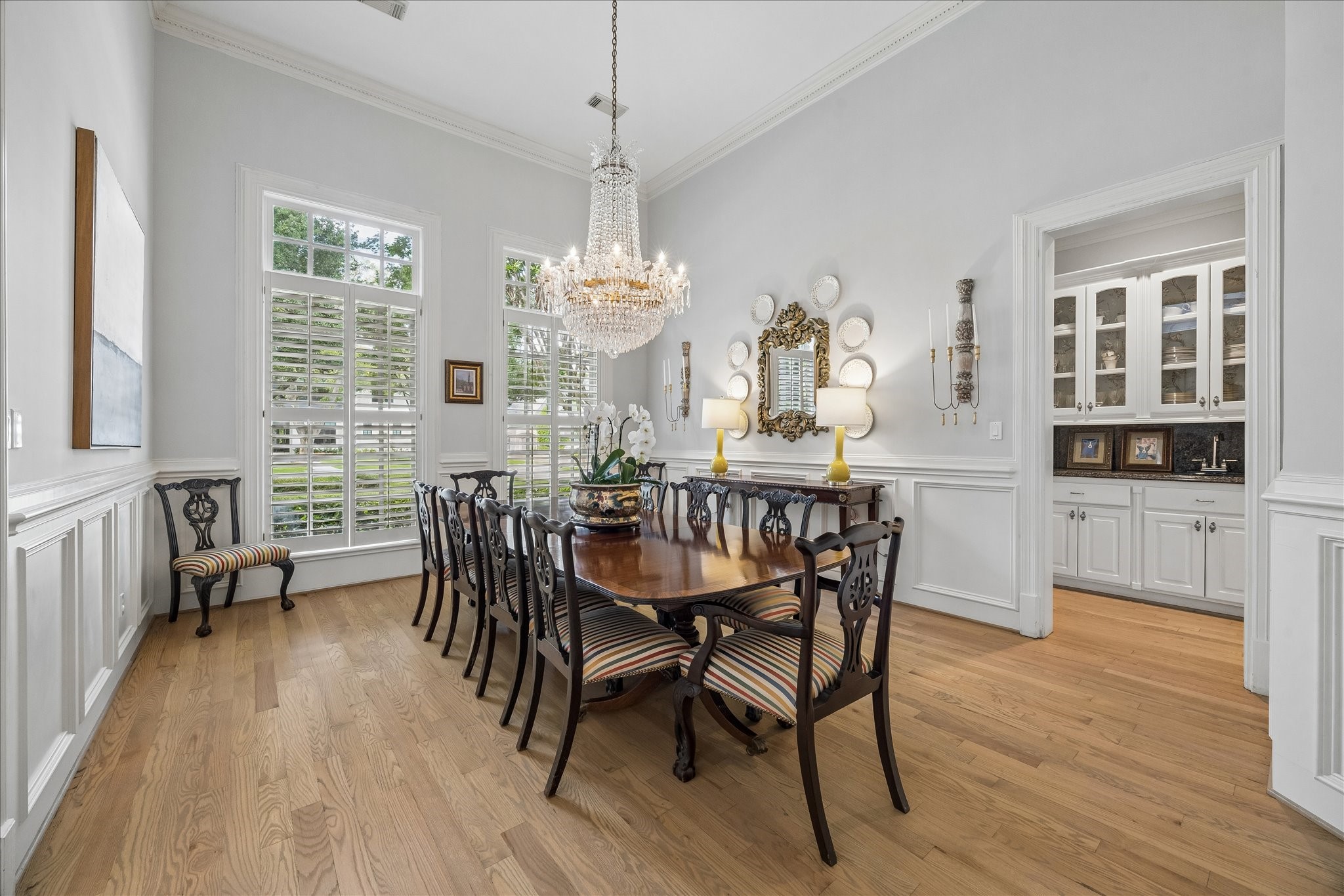 11421 Whippoorwill Road Houston, TX 77024 - Photo 7 of 33 Host unforgettable dinners in this sophisticated formal dining room, featuring timeless wainscoting, gleaming hardwood floors, and an abundance of natural light through large shuttered windows. The seamless flow into the butler's pantry makes entertaining effortless