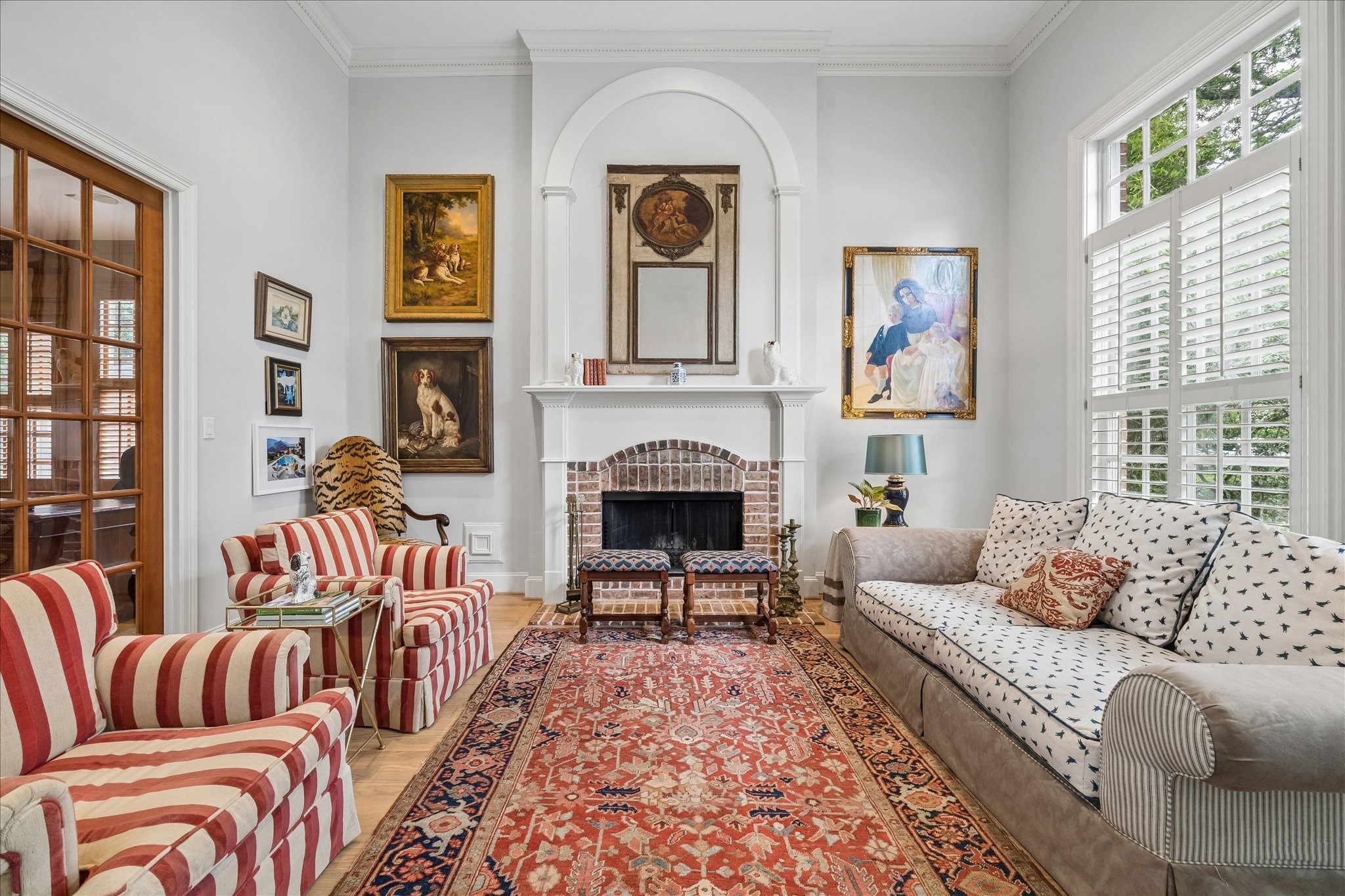 11421 Whippoorwill Road Houston, TX 77024 - Photo 9 of 33 Sophisticated formal living room featuring a stately wood burning fireplace and soaring ceilings. Beautifully transitions to the home office through glass-front French doors. Bright, airy, and accented by custom millwork and plantation shutters
