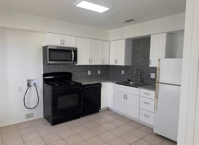 a kitchen with white cabinets stainless steel appliances and a sink
