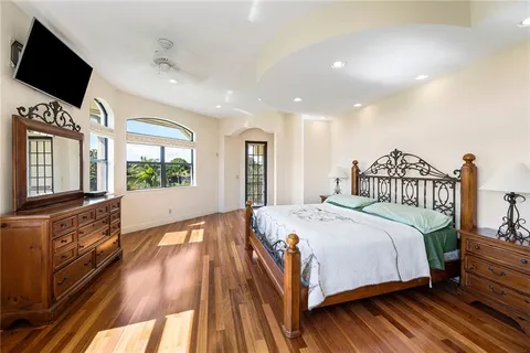 a bedroom with a large bed and a flat tv screen on dresser