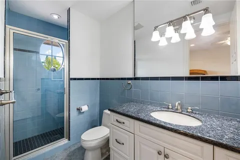 a bathroom with a granite countertop sink a toilet and a mirror