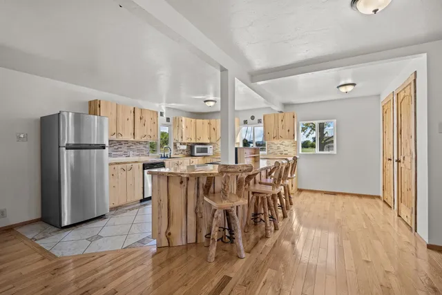 a kitchen with stainless steel appliances a dining table chairs refrigerator and cabinets