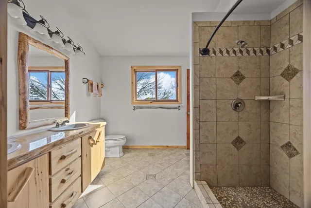 a bathroom with a granite countertop sink a toilet a mirror a window and vanity