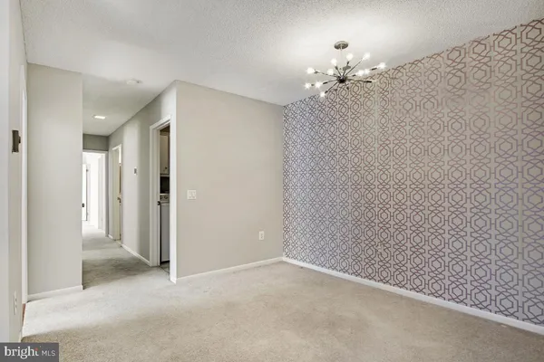 a view of an empty room with a chandelier fan