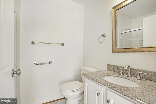 a bathroom with a granite countertop sink toilet and mirror