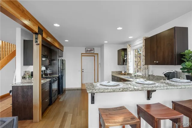 a kitchen with kitchen island granite countertop a sink cabinets and stainless steel appliances