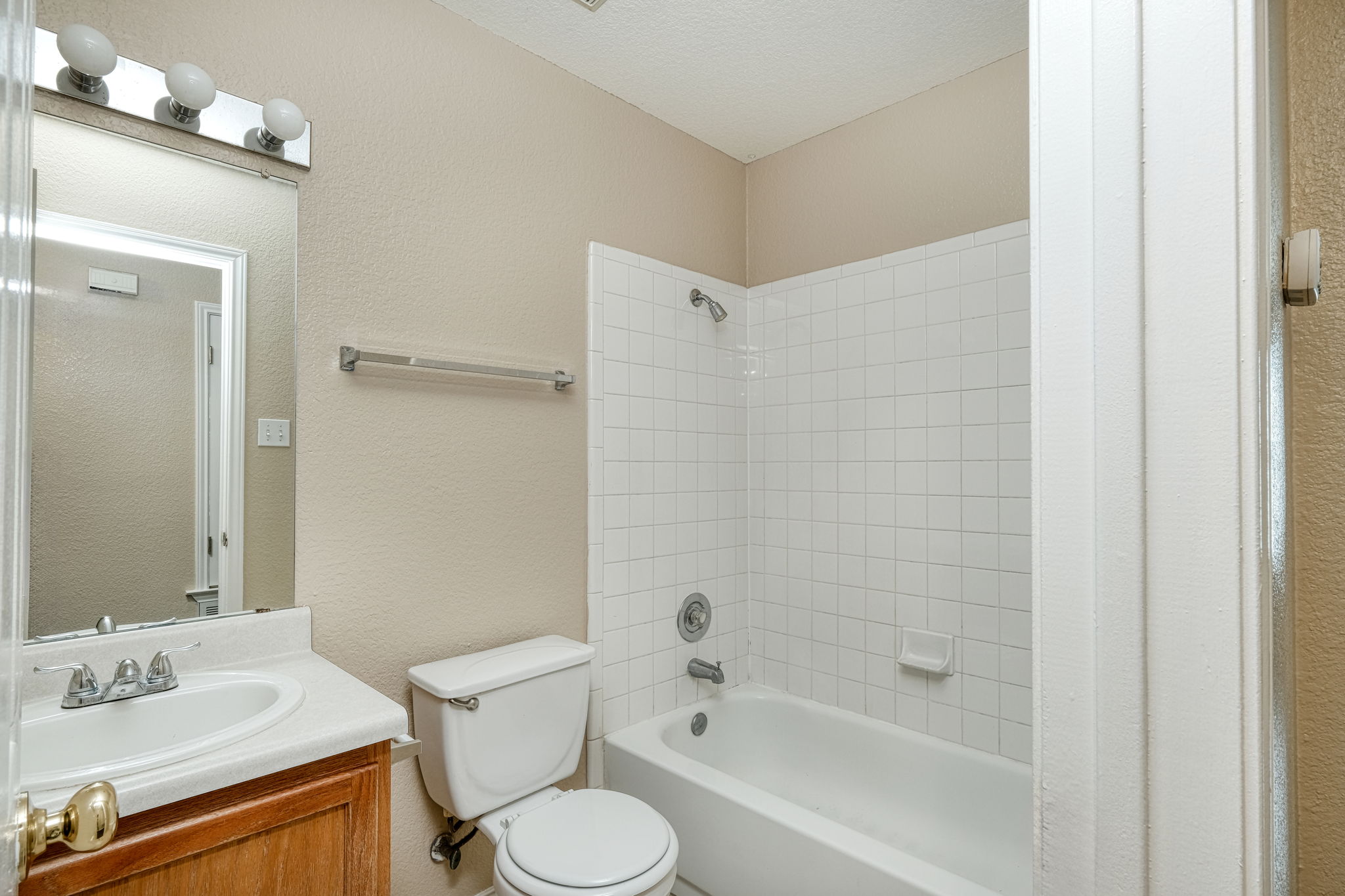 124 Hunter Rex Way Kyle, TX 78640 - Photo 10 of 14 Full bathroom featuring a white bathtub with subway tile surround, a single vanity with wood-finish cabinetry, and a chrome-finish light fixture