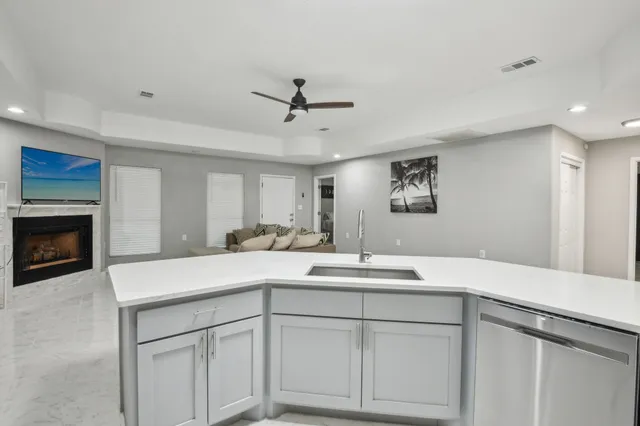 a view of kitchen with stainless steel appliances granite countertop a stove a sink dishwasher and white cabinets with wooden floor