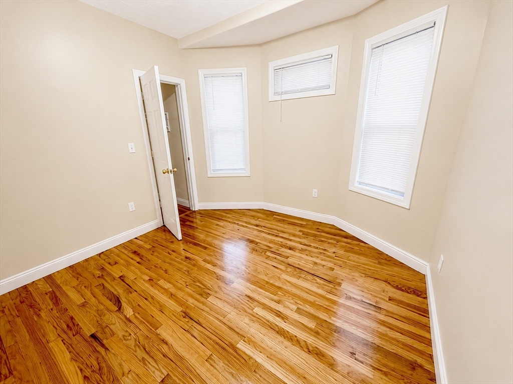 19 Dunlap Street, Unit 1 Boston, MA 02124 - Photo 3 of 9 an empty room with wooden floor and windows