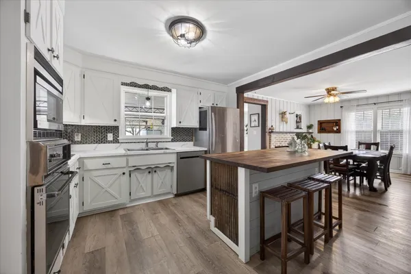 a kitchen with stove a sink dishwasher a dining table and chairs with wooden floor