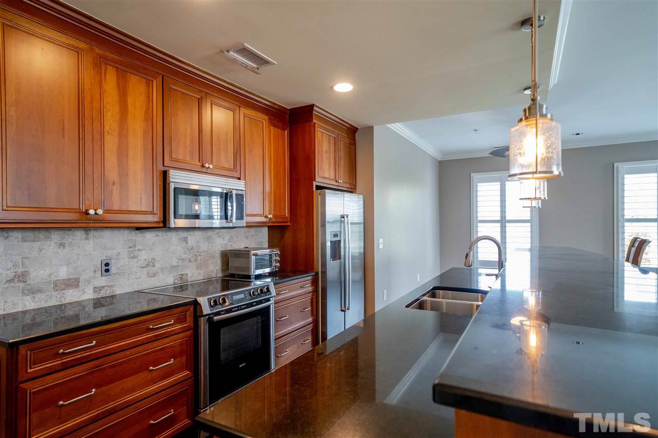 710 Independence Place, Unit 407 Raleigh, NC 27603 - Photo 4 of 27 a kitchen with stainless steel appliances granite countertop a refrigerator a sink dishwasher a stove and white countertops with wooden floor