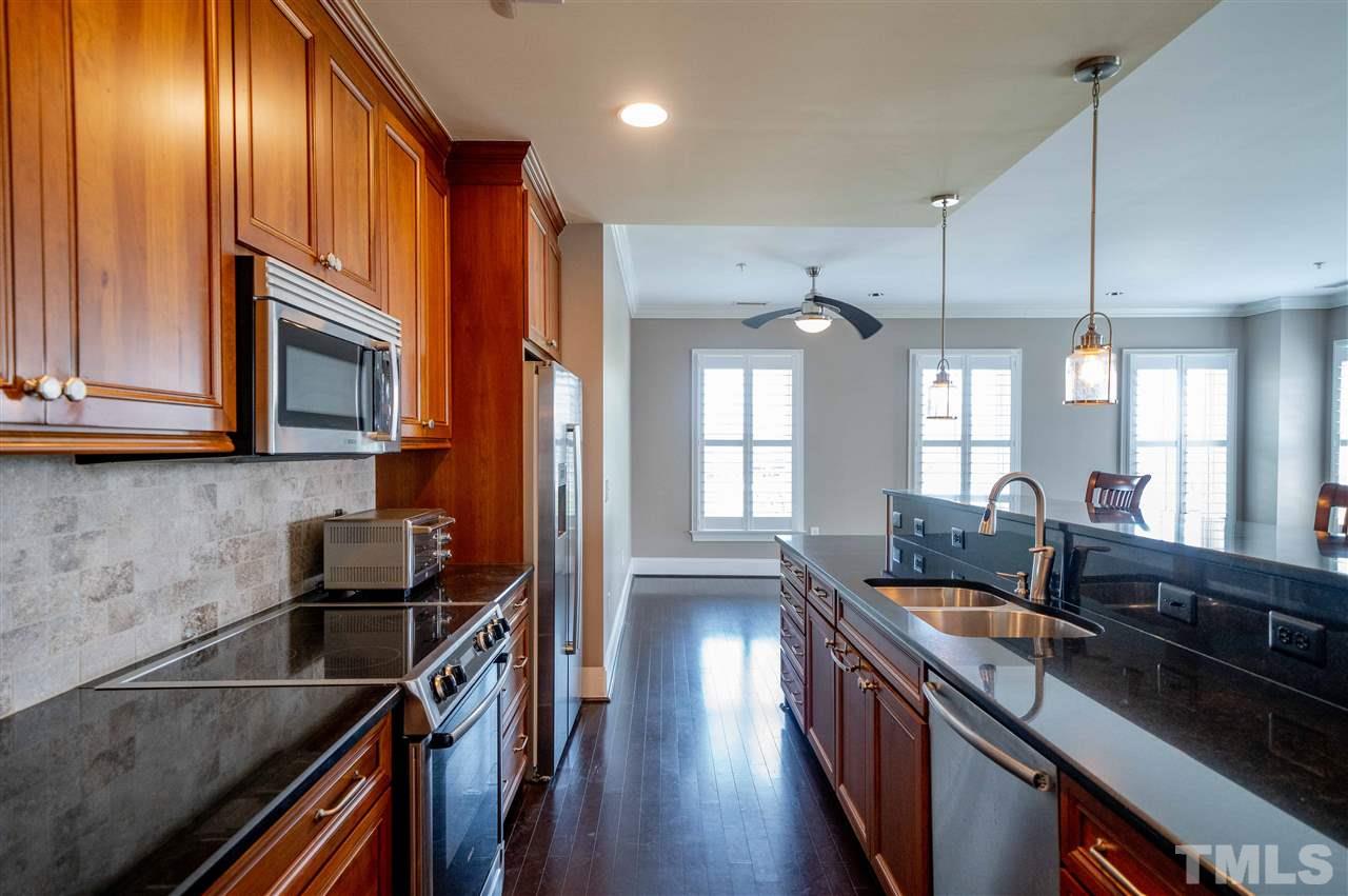710 Independence Place, Unit 407 Raleigh, NC 27603 - Photo 5 of 27 a kitchen with granite countertop a stove a sink and a refrigerator