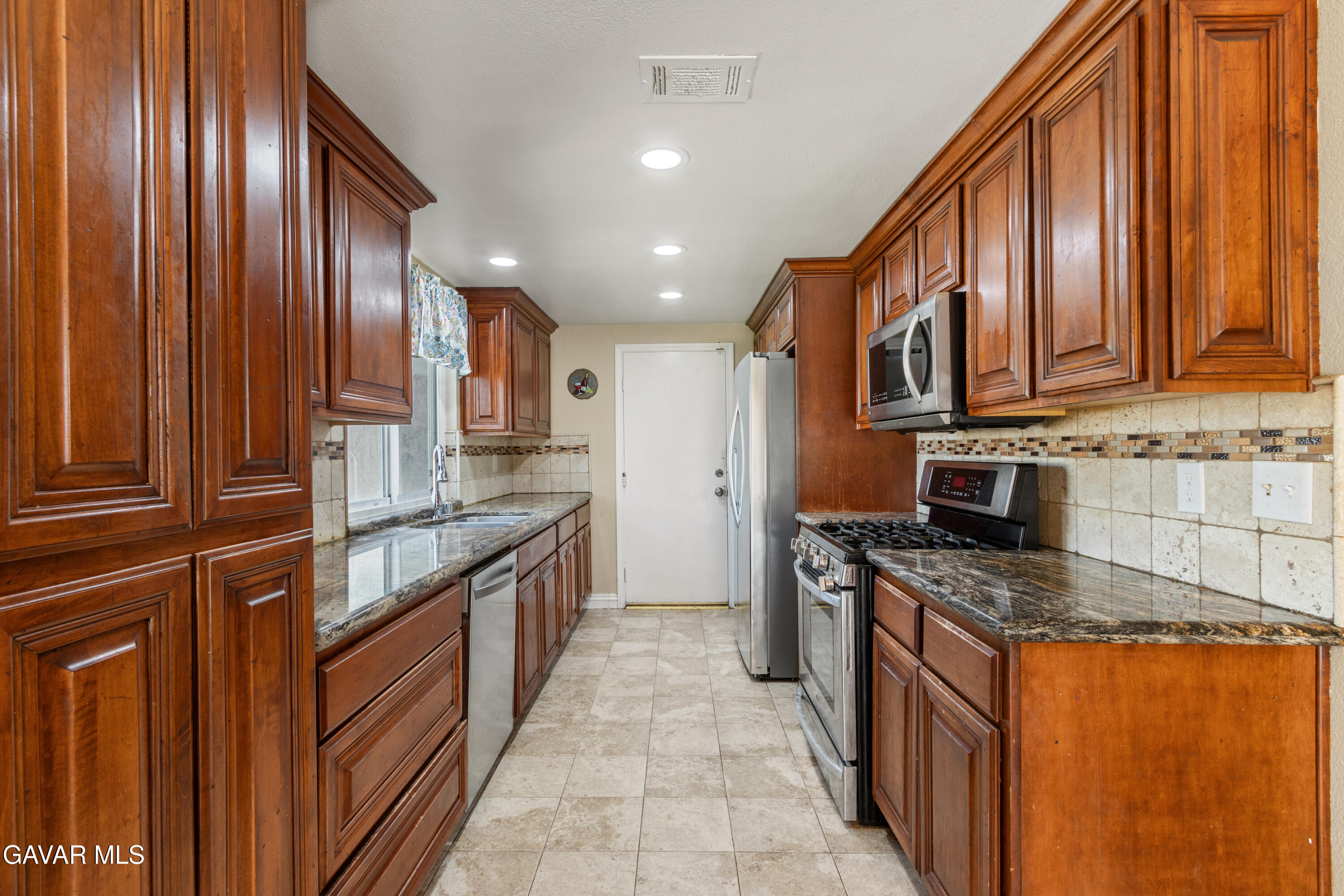 2128 Edam Street Lancaster, CA 93536 - Photo 9 of 26 a kitchen with stainless steel appliances granite countertop wooden cabinets a sink and dishwasher a oven with wooden cabinets