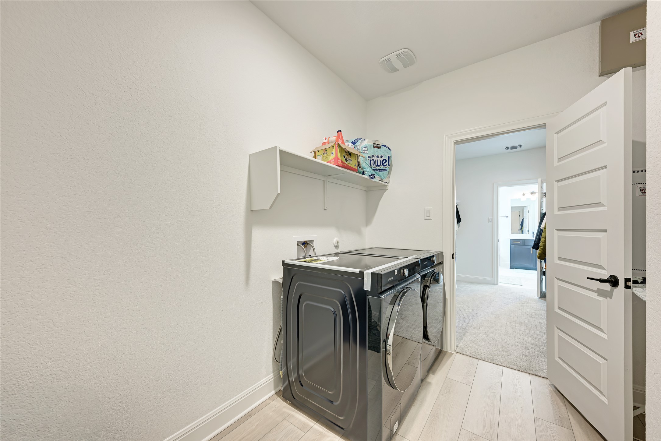 316 Regatta Trail Leander, TX 78641 - Photo 23 of 39 Dedicated laundry area featuring wood-finish flooring, a contemporary white door with matte black hardware, and a built-in wall shelf
