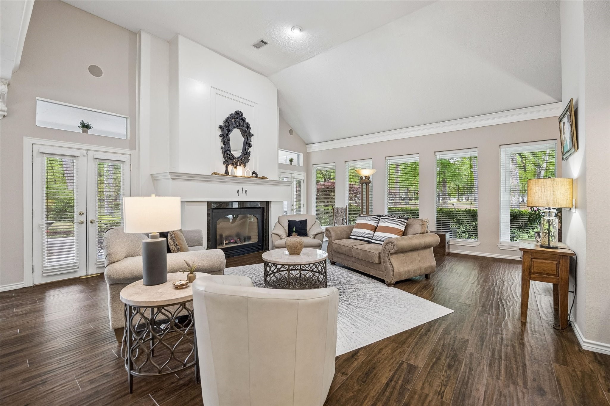 502 Monitor Park Conroe, TX 77302 - Photo 2 of 26 At the heart of the home, the family room is grounded by a gas log fireplace and flows seamlessly into the kitchen and dining room. High ceilings and a wall of windows invite in endless natural light and lush greenery.
The family room unfolds effortlessly into the kitchen, where soaring ceilings and a gas log fireplace create a sense of quiet grandeur, while a wall of windows washes the space in soft, natural light throughout the day.