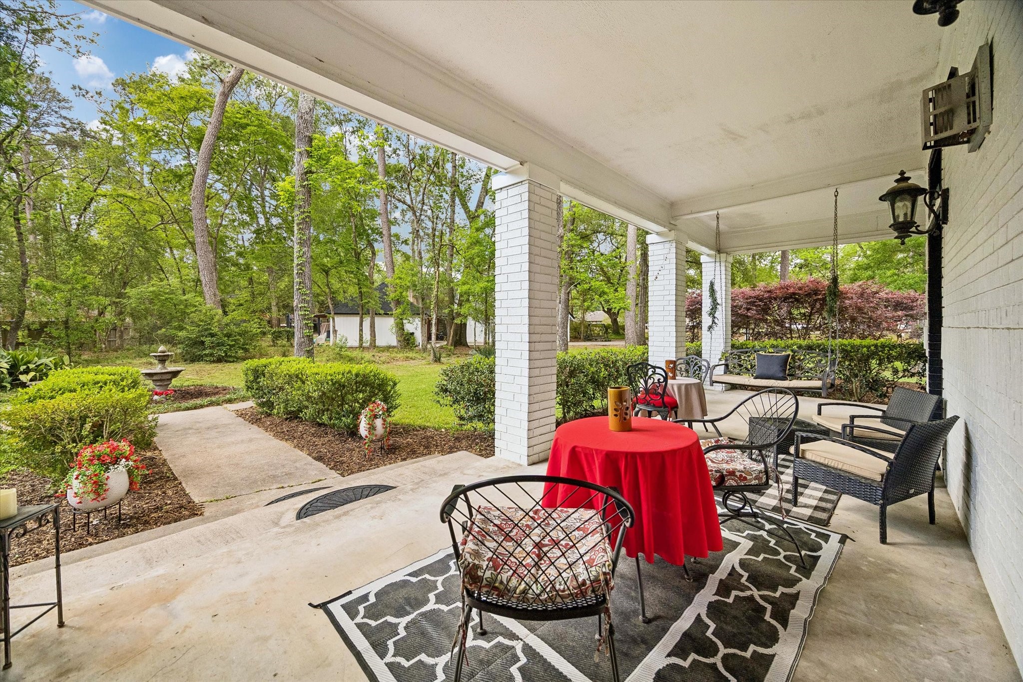 502 Monitor Park Conroe, TX 77302 - Photo 3 of 26 A wraparound porch that feels like its own little escape. Anchored by a hanging swing bench and a softly trickling water fountain, creating the kind of setting where mornings linger and evenings slow down effortlessly.