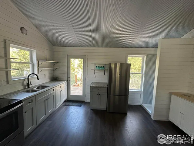a kitchen with stainless steel appliances granite countertop a refrigerator a sink dishwasher a stove and white countertops with wooden floor