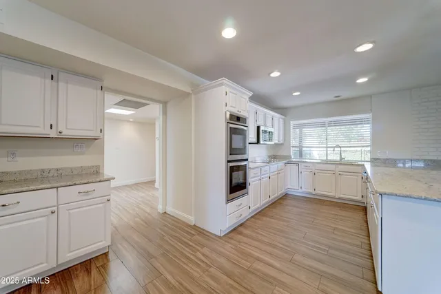 a kitchen with white cabinets and wooden floor