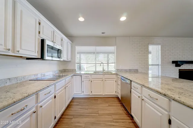 a large kitchen with stainless steel appliances granite countertop a sink and dishwasher a stove top oven with wooden floor