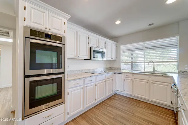 a kitchen with granite countertop white cabinets stainless steel appliances and sink
