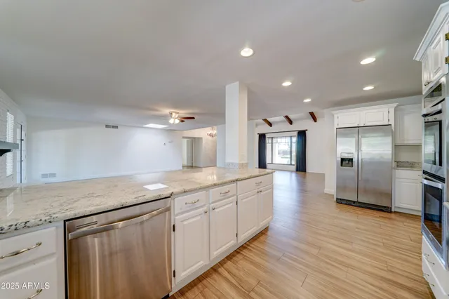 a large kitchen with stainless steel appliances granite countertop a large counter top a sink and a refrigerator