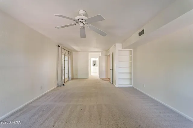 a view of an empty room with a chandelier fan