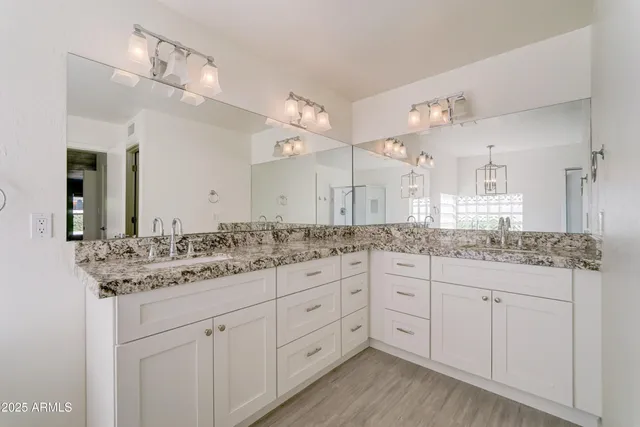 a bathroom with a granite countertop double vanity sink and a mirror