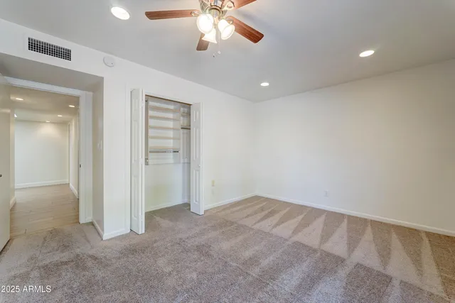 an empty room with closet and a chandelier fan