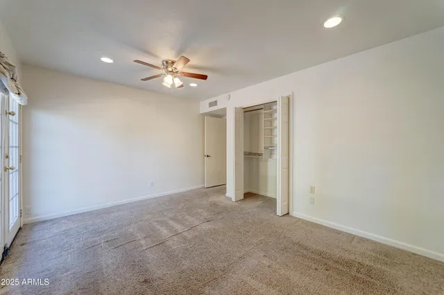 an empty room with closet and a ceiling fan
