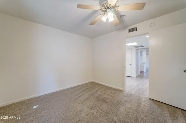 wooden floor in an empty room with a chandelier fan