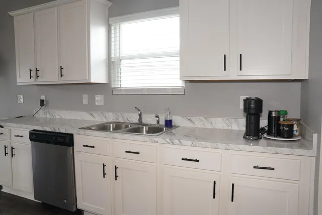 a kitchen with white cabinets and a window