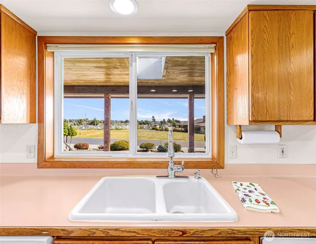 a view of a kitchen with kitchen island a large window and a sink