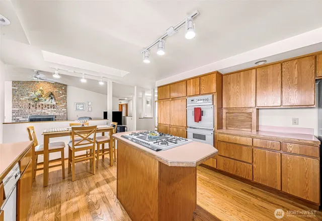 a open kitchen with stainless steel appliances granite countertop a stove a refrigerator a dining table and chairs with wooden floor