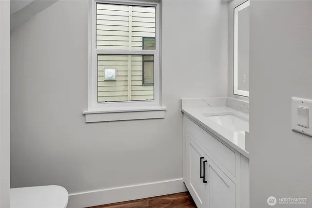 a bathroom with a granite countertop sink toilet and a window