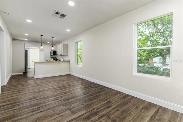 a view of empty room with wooden floor and fan