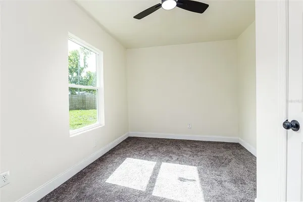 an empty room with a window and a ceiling fan