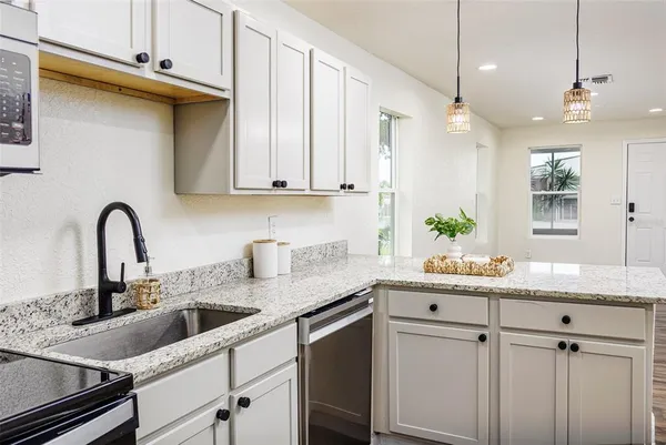 a kitchen with stainless steel appliances granite countertop a stove a sink and white cabinets