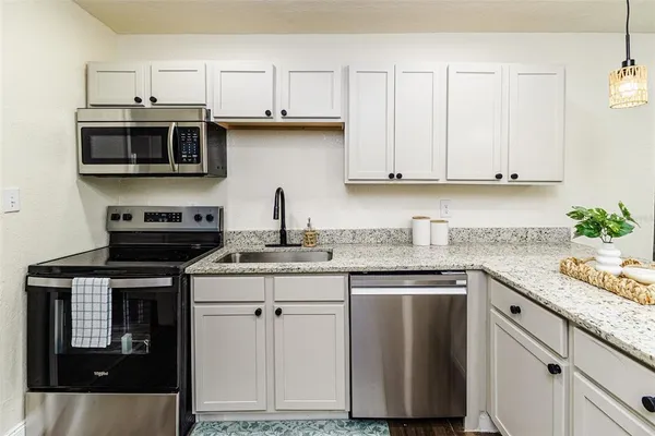 a kitchen with stainless steel appliances granite countertop a stove a sink dishwasher and microwave with wooden floor