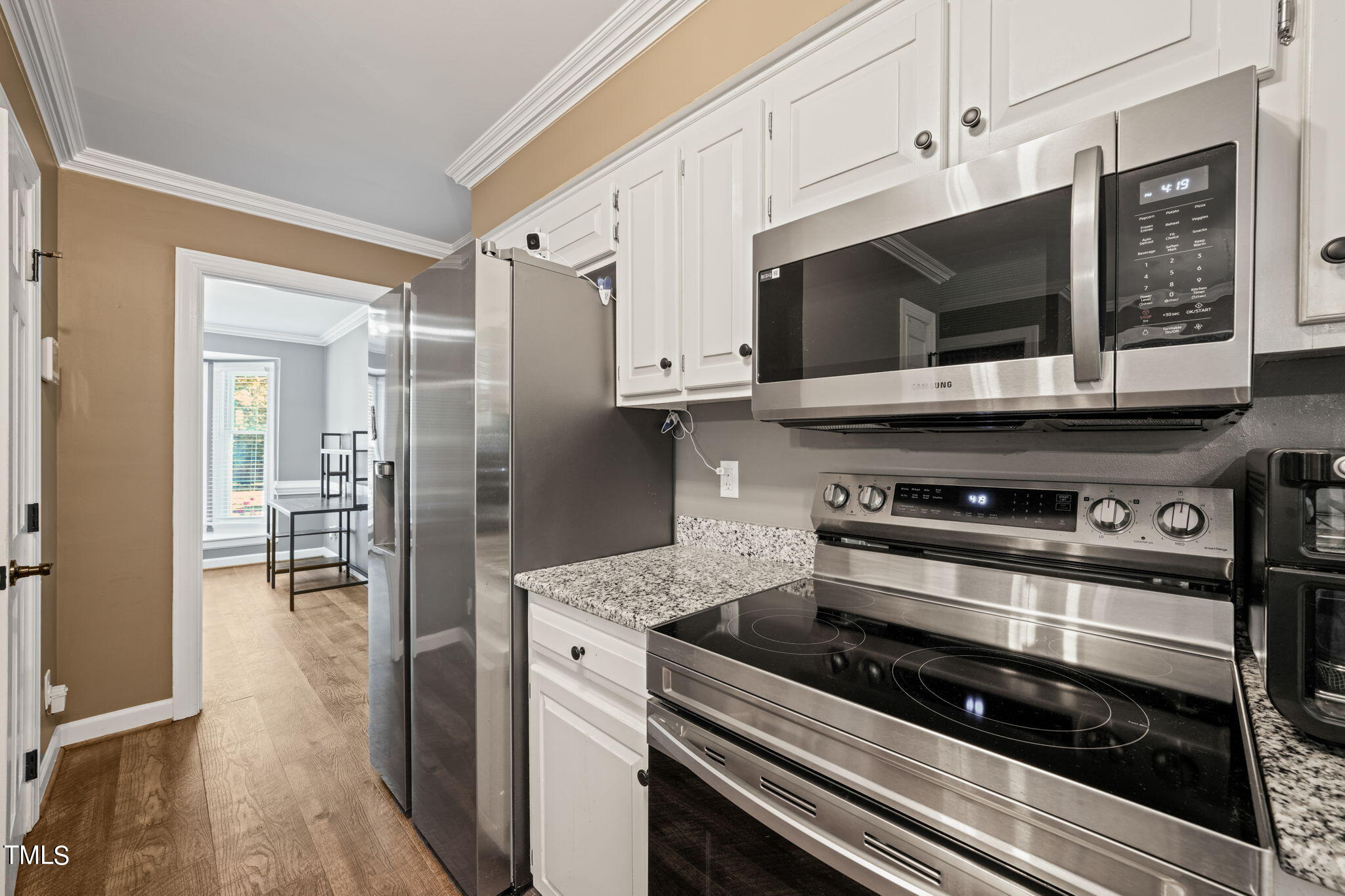 7125 Sandringham Drive Raleigh, NC 27613 - Photo 9 of 26 a kitchen with stainless steel appliances kitchen island granite countertop a stove and a microwave