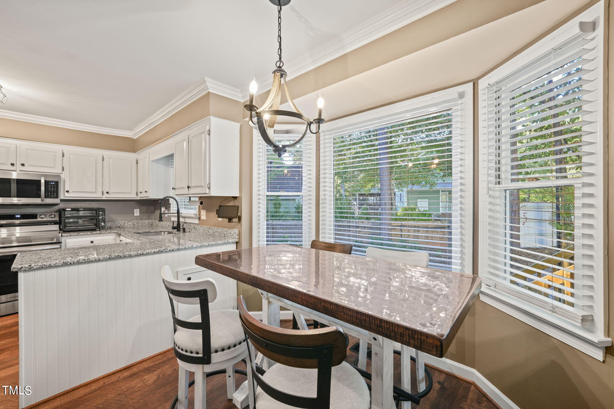 7125 Sandringham Drive Raleigh, NC 27613 - Photo 10 of 26 a kitchen with stainless steel appliances granite countertop a stove a refrigerator a kitchen island with a stove and white cabinets