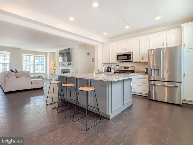 a kitchen with stainless steel appliances a refrigerator a stove a sink a dining table and chairs