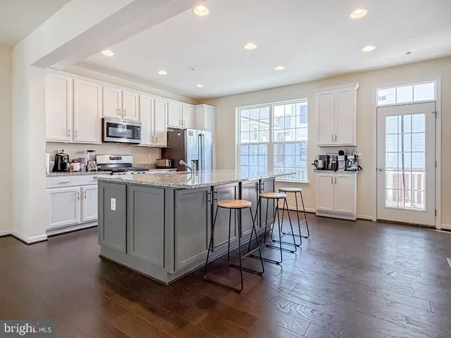 a kitchen with stainless steel appliances granite countertop a stove a sink dishwasher a refrigerator and a microwave oven with wooden floor