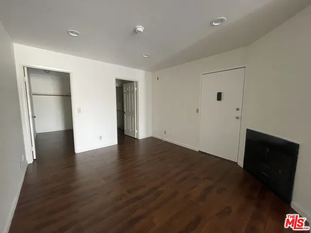 a view of an empty room with wooden floor and a cabinet