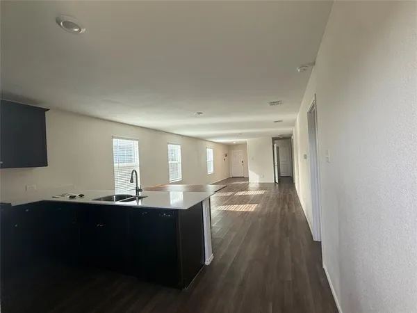 a living room with stainless steel appliances kitchen island granite countertop a sink and wooden floor