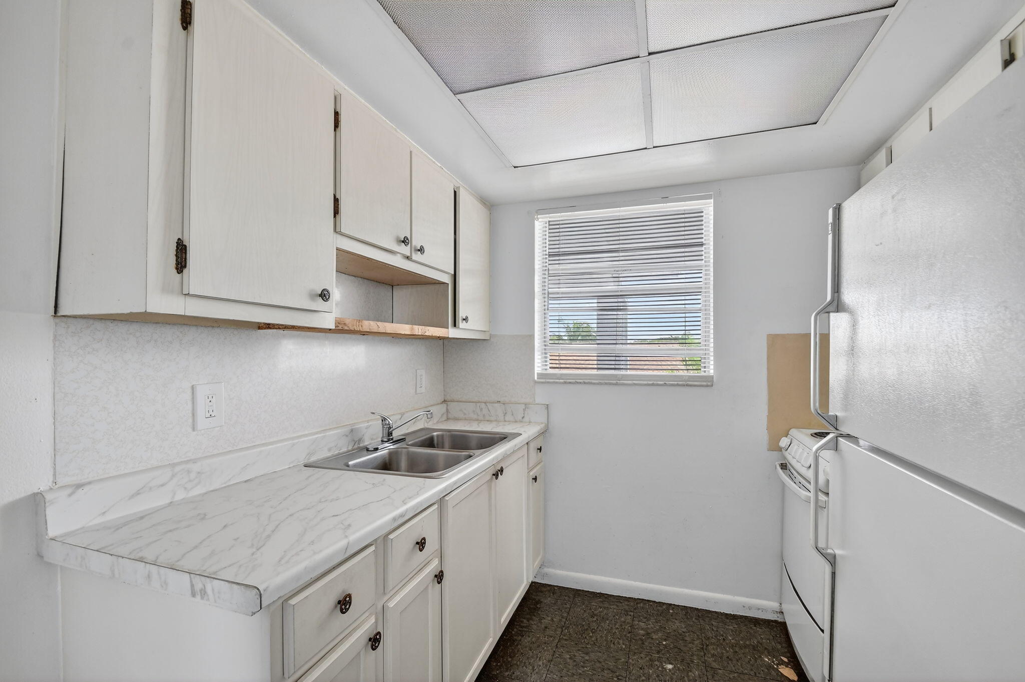 1406 Barton Road, Unit 15 Lake Worth Beach, FL 33460 - Photo 11 of 19 a kitchen with stainless steel appliances granite countertop white cabinets and window