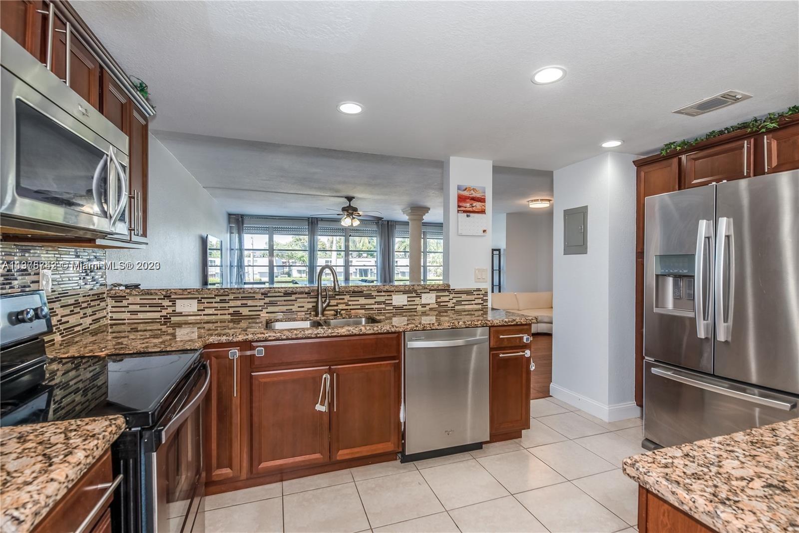a kitchen with stainless steel appliances granite countertop a stove top oven microwave and refrigerator