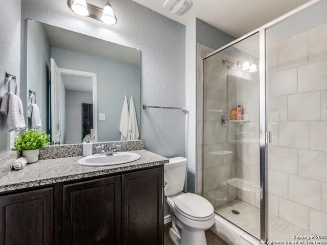 a bathroom with a granite countertop sink toilet and shower